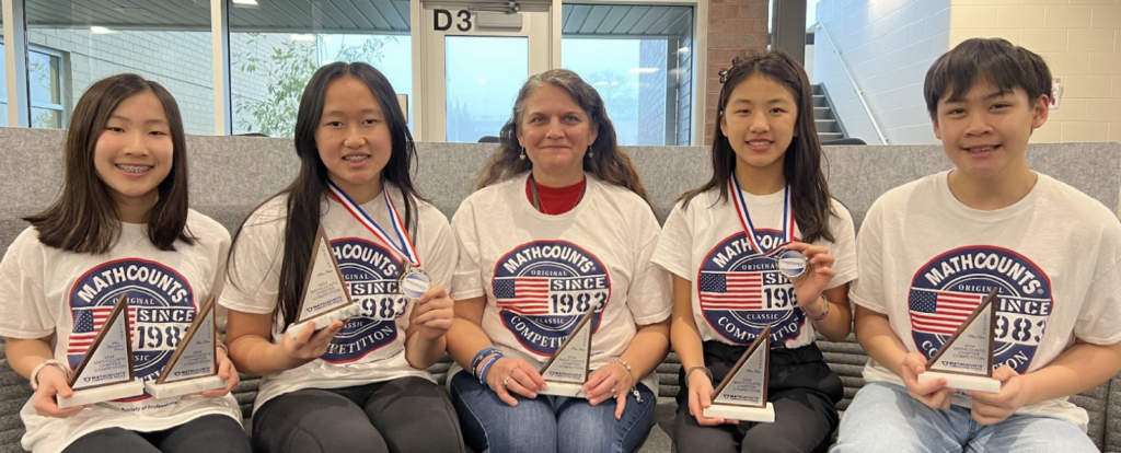 students and a teacher sitting on the couch with awards in their hand